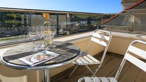 A round metal table with a glass top, surrounded by metal chairs, on a balcony with a glass railing. - 6 Chichester Court (Kingsbridge)