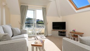 A living room with a sofa, a coffee table, a TV, and a balcony with curtains. - 6 Chichester Court (Kingsbridge)