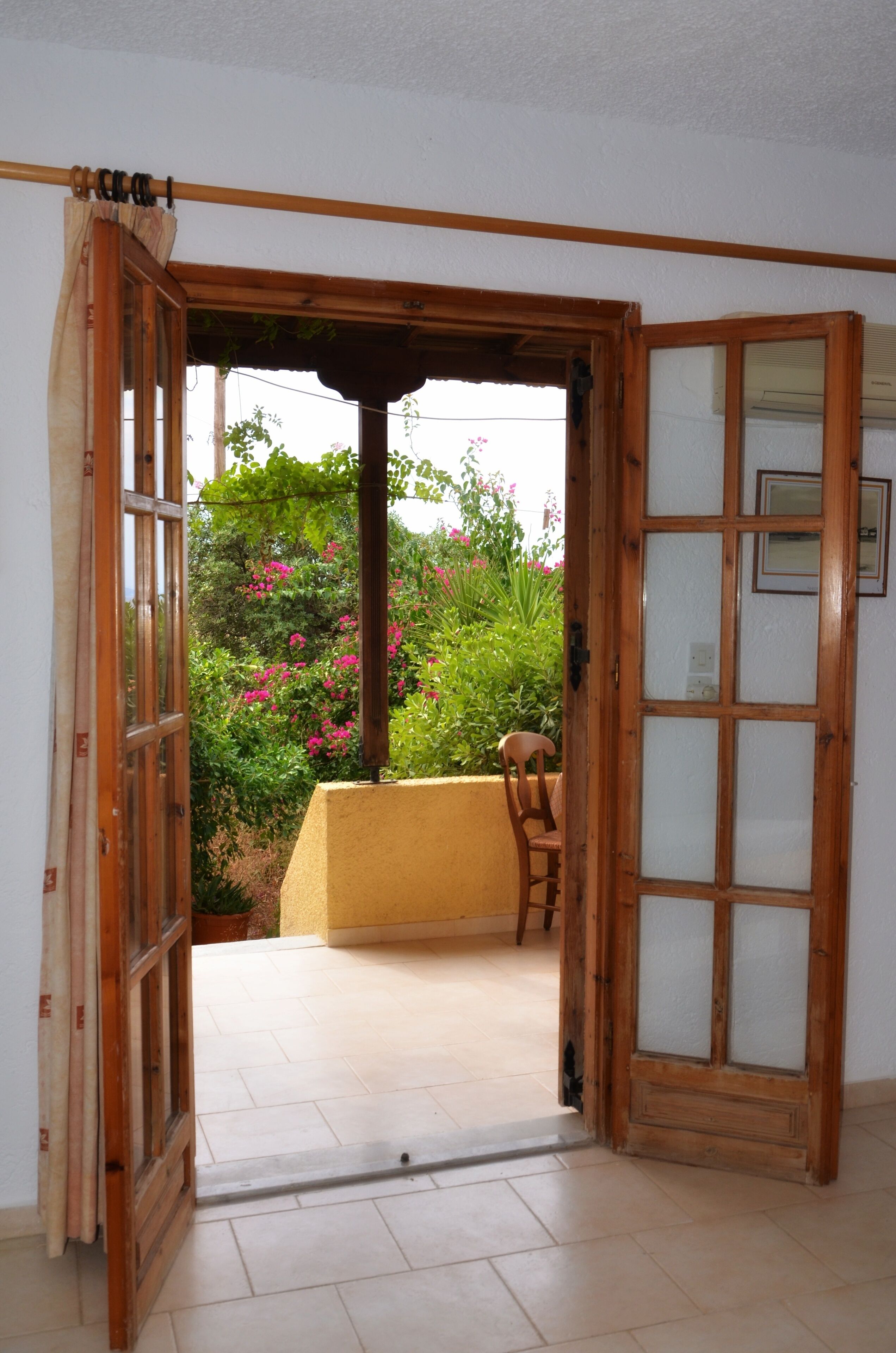 Una puerta abierta que da a un balcón con vistas a un jardín.
