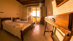 A bedroom with two wooden beds, a wooden dresser, and a view of the outside through a window. - Vagia Beach Apartments (Aegina)