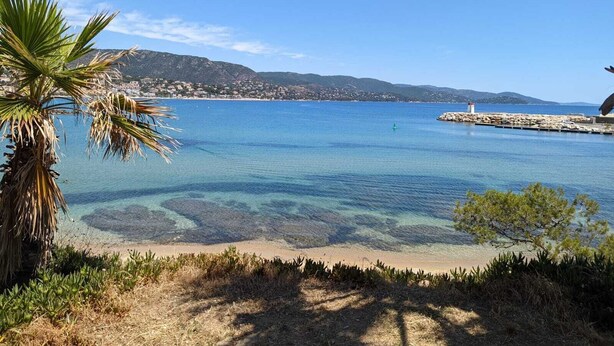 A coastal view with clear water, a sandy beach, and a distant town. - 1bed Apartment Sleeps 4 - Sea Views, Wifi, Parking (Bormes Les Mimosas)