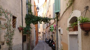 A narrow cobblestone street lined with buildings, some with balconies and potted plants. - 1bed Apartment Sleeps 4 - Sea Views, Wifi, Parking (Bormes Les Mimosas)