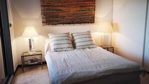 A bedroom with a bed, two bedside tables with lamps, a large abstract artwork on the wall, and a window on the left. - 1bed Apartment Sleeps 4 - Sea Views, Wifi, Parking (Bormes Les Mimosas)