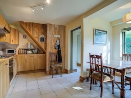 Una cocina con armarios de madera, un microondas y un comedor con mesa y sillas.