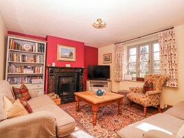 Una sala de estar con chimenea, una estantería, un televisor y un sillón con estampado floral.
