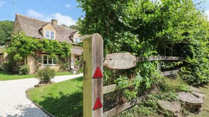 A wooden post with a sign indicating a cottage. - Orchard Cottage (Broadway)