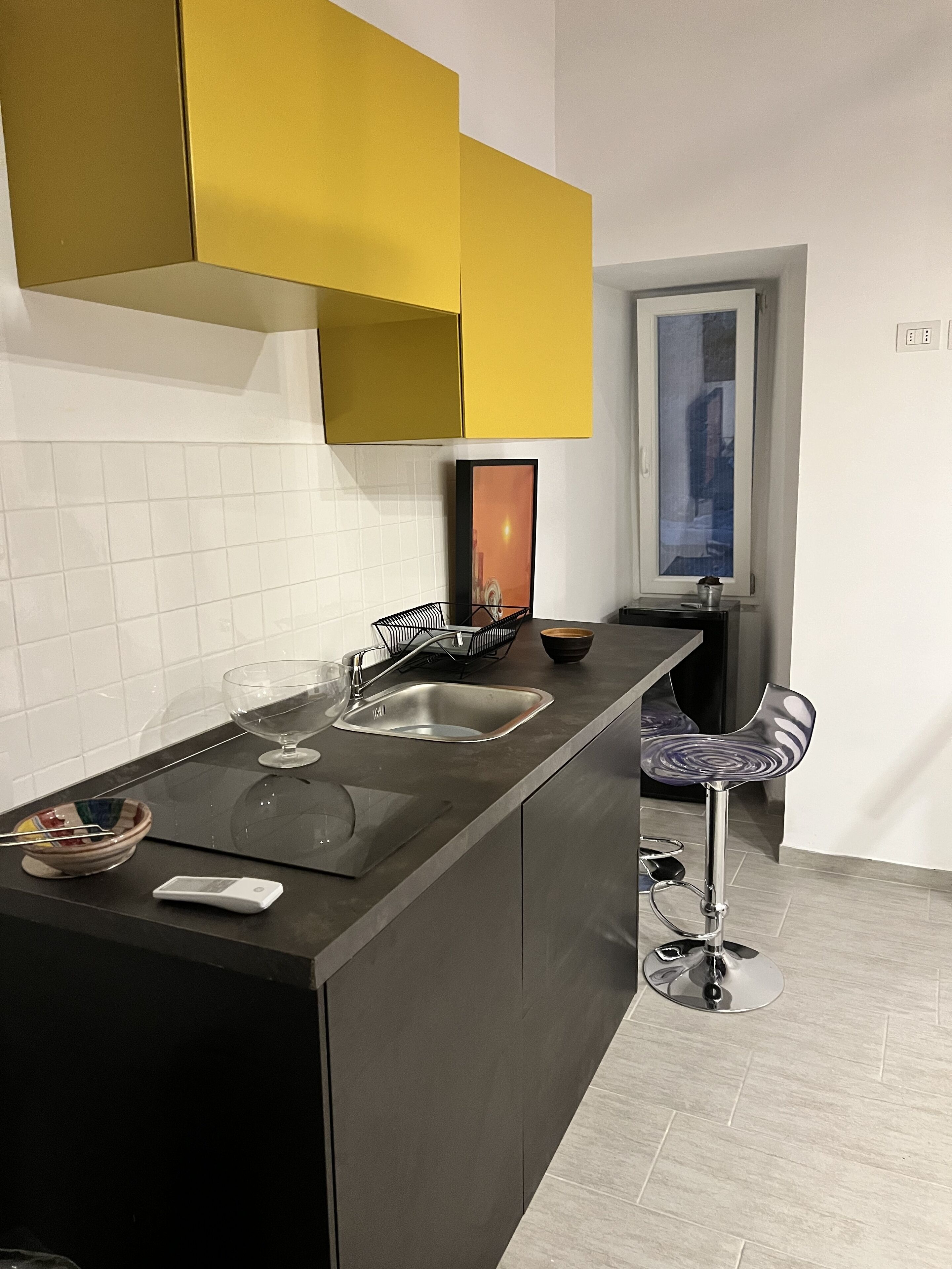 A modern kitchen with a central island, a bar stool, and a window with a view.