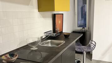 A modern kitchen with a central island, a bar stool, and a window with a view.