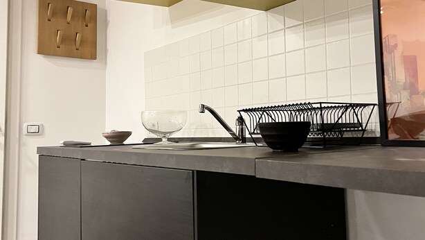 A modern kitchen with a grey countertop, a black sink, and a glass bowl.