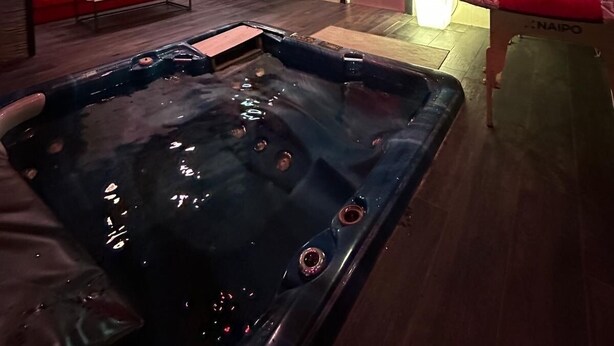 Ein moderner Wellnessraum mit Whirlpool, roten Sitzgelegenheiten und stimmungsvoller Beleuchtung.