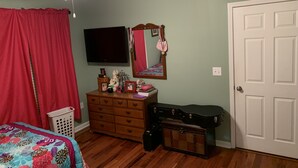 A bedroom with a bed, dresser, guitar, and a TV. - Luxurious Condominium (Dunwoody)