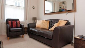 A living room with a dark brown leather sofa, a black leather armchair, and a large mirror on the wall. - Aeolus House (Dartmouth)
