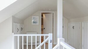 Un dormitorio amplio en áticos con techo inclinado, paredes blancas y un tragaluz grande.