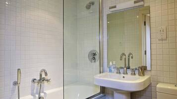 A modern bathroom with a glass-enclosed shower, a white bathtub, and a sink with a mirror above it.