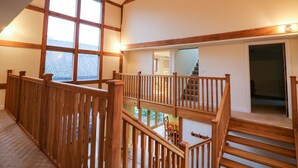 Un intérieur spacieux avec un plafond haut, des poutres en bois et un escalier menant à un niveau supérieur.