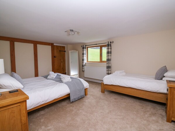 A room with two wooden beds, a mirror, a window with curtains, and a radiator.