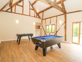 Una habitación con mesa de billar, mesa de fútbol de mesa y dardos.