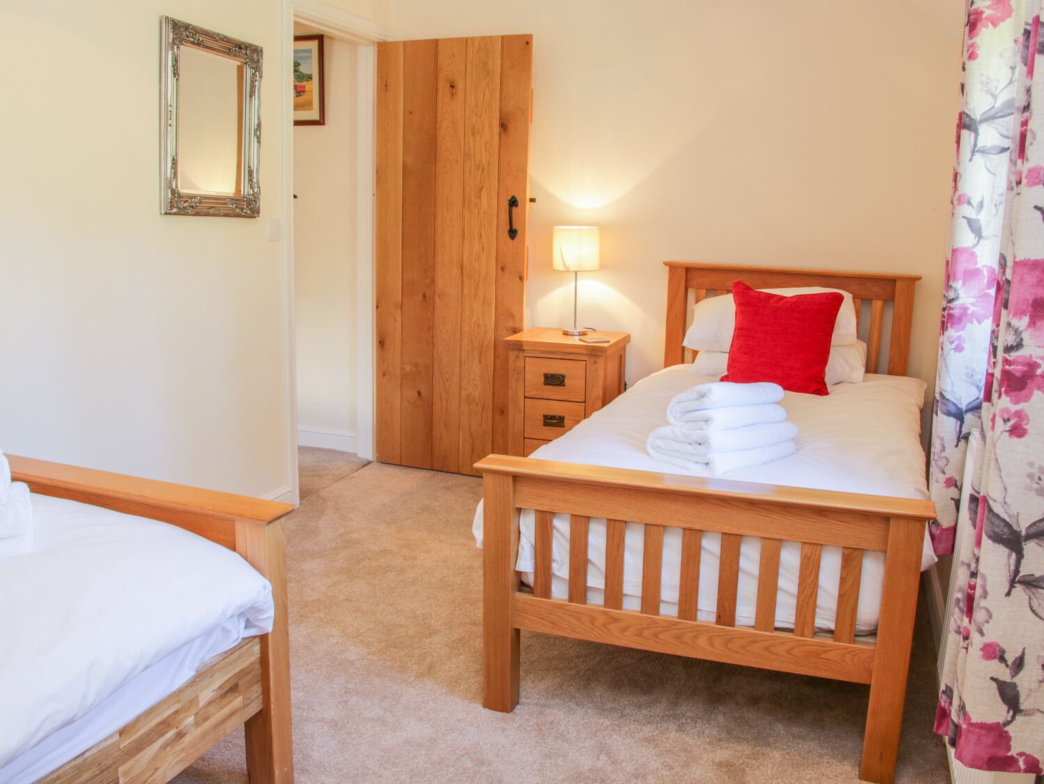 Un dormitorio con una cama de madera, una mesita de noche, una lámpara y una puerta.