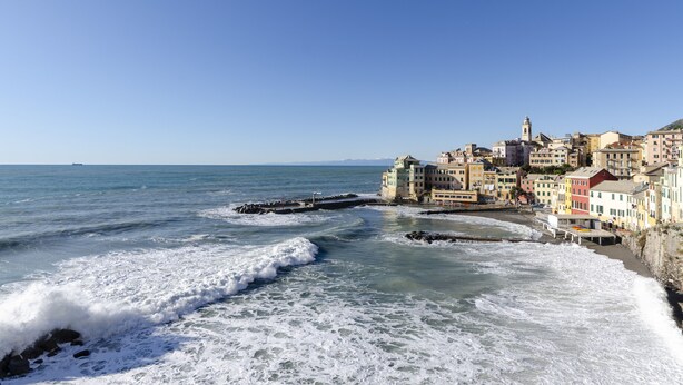 Une ville côtière avec des bâtiments qui bordent la plage, un ciel dégagé et des vagues qui se brisent sur le sable.