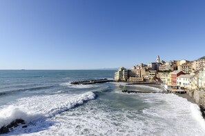 Une ville côtière avec des bâtiments qui bordent la plage, un ciel dégagé et des vagues qui se brisent sur le sable.
