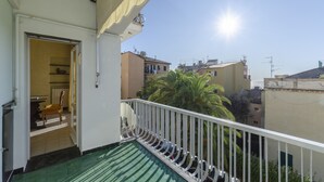 Un balcon offrant une vue sur les immeubles voisins et un ciel dégagé.