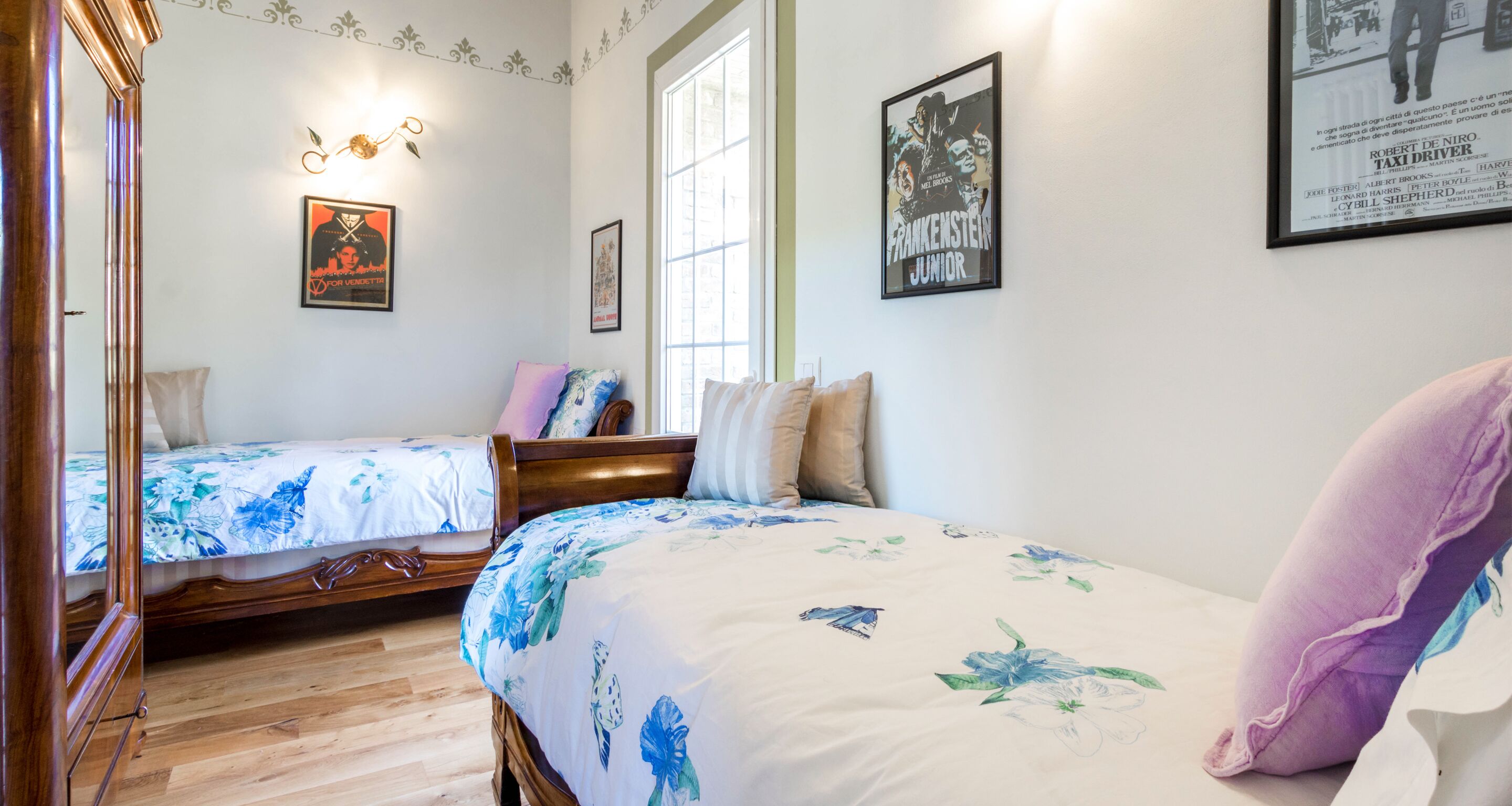 Un dormitorio con dos camas individuales, un armario de madera y un ventanal grande.