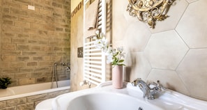A bathroom with a white sink, a shower, and a bathtub. There is a white towel rack and a decorative wall piece.