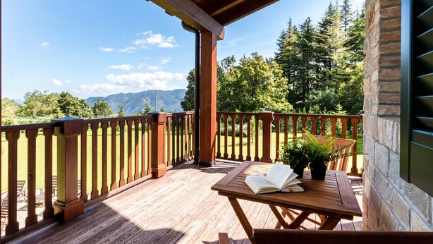 Une terrasse en bois avec une table et des chaises, un livre et des plantes en pot.