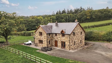 A stone farmhouse with a fenced yard and a gravel driveway.