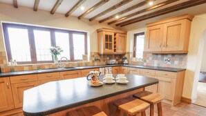 Una cocina con gabinetes de madera, una isla grande con taburetes, un salpicadero de azulejos y una ventana con vistas.