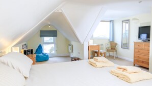 Ein Schlafzimmer mit einem großen Bett, einem Schreibtisch, einem Sessel, einer Kommode und einem Fernseher.