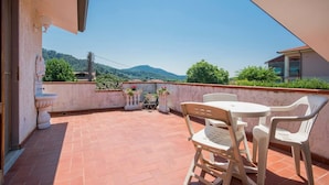 Une terrasse avec une table et des chaises, des toilettes et des plantes en pot.