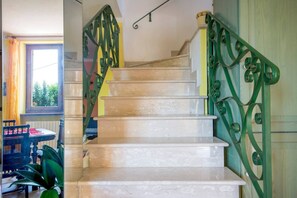 A staircase with green metal railings and a view of a room with a window and a table. - JOIVY Shared Villa Nature&relax (Massarosa)
