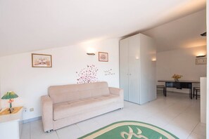 A modern living room with a beige sofa, a dining table with chairs, and a white wardrobe. - JOIVY Shared Villa Nature&relax (Massarosa)