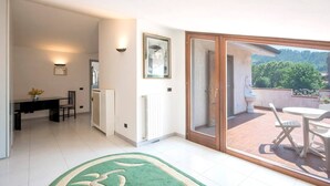 Un appartement moderne comprenant un coin repas, un radiateur, un tableau encadré et un balcon aménagé avec du mobilier d’extérieur.