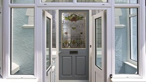 Una porta d'ingresso con un vetro decorativo e un disegno in metallo.
