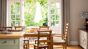 A dining area with a wooden table and chairs, a basket, and breakfast items. - Orchard House (Moreton-in-Marsh)