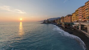 A coastal cityscape with buildings along the waterfront, a clear sky, and the sun setting or rising over the sea. - JOIVY Camogli il Terrazzino e il Mare (Camogli)
