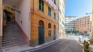 A narrow street with a building featuring a staircase, green doors, and a number '36' sign. - JOIVY Camogli il Terrazzino e il Mare (Camogli)