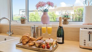 A kitchen counter with croissants, strawberries, champagne, and orange juice glasses. - Chi An Mor (Newquay)
