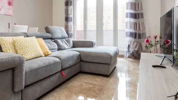 A modern living room with a grey sectional sofa, a flat-screen TV, and a wooden coffee table. - JOIVY Milano Fiera Cozy & Elegant Apartment (Milan)