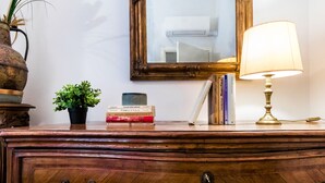 A wooden dresser with a lamp, books, a potted plant, and a mirror.