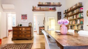 A well-lit room with a wooden dining table, a bookshelf, and a decorative vase.