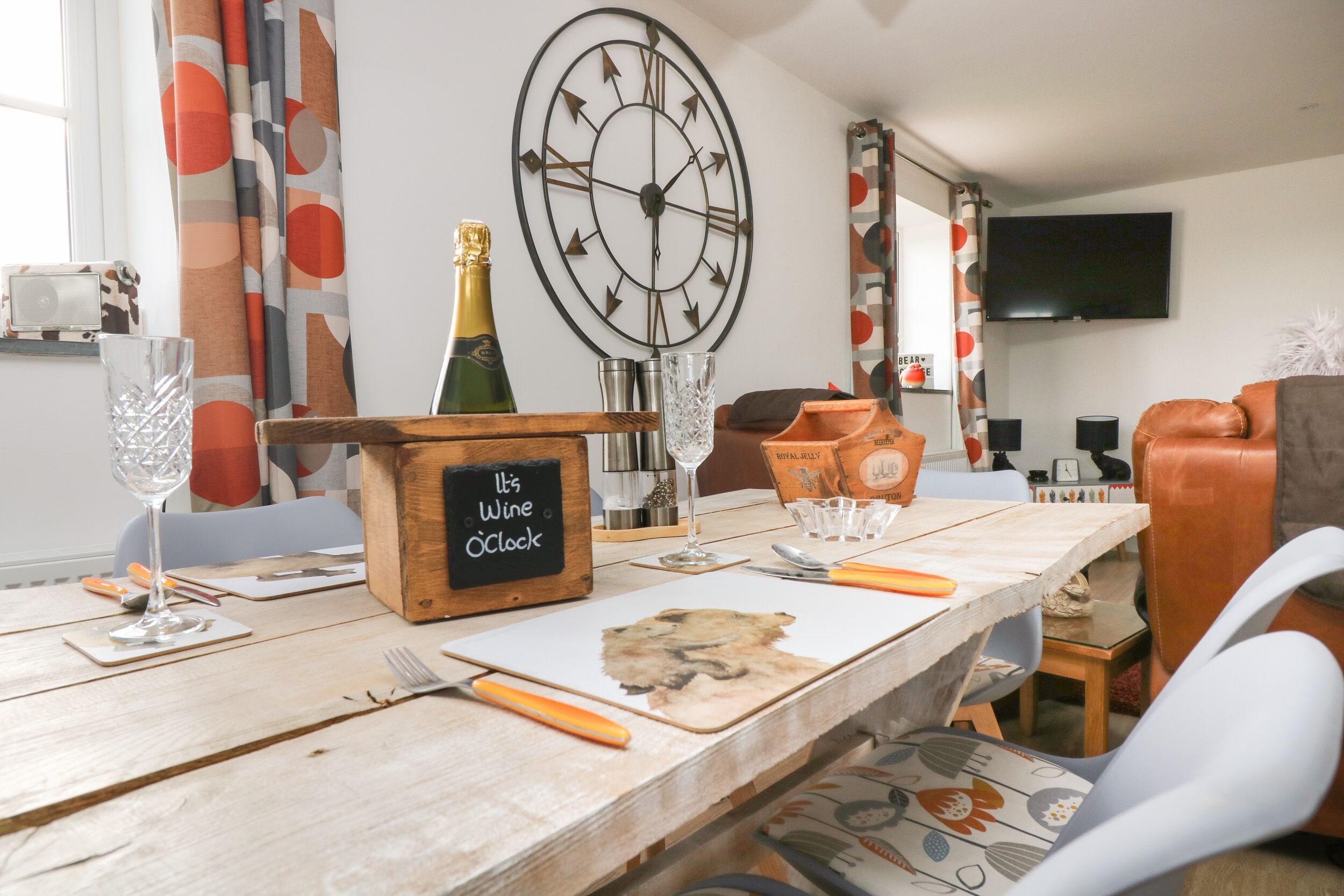 A dining table set with cutlery, a wine bottle, glasses, and a clock labeled 'It's Wine O'Clock'.