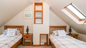 Camera da letto con due letti, un lucernario, un quadro incorniciato e un comodino con lampada.