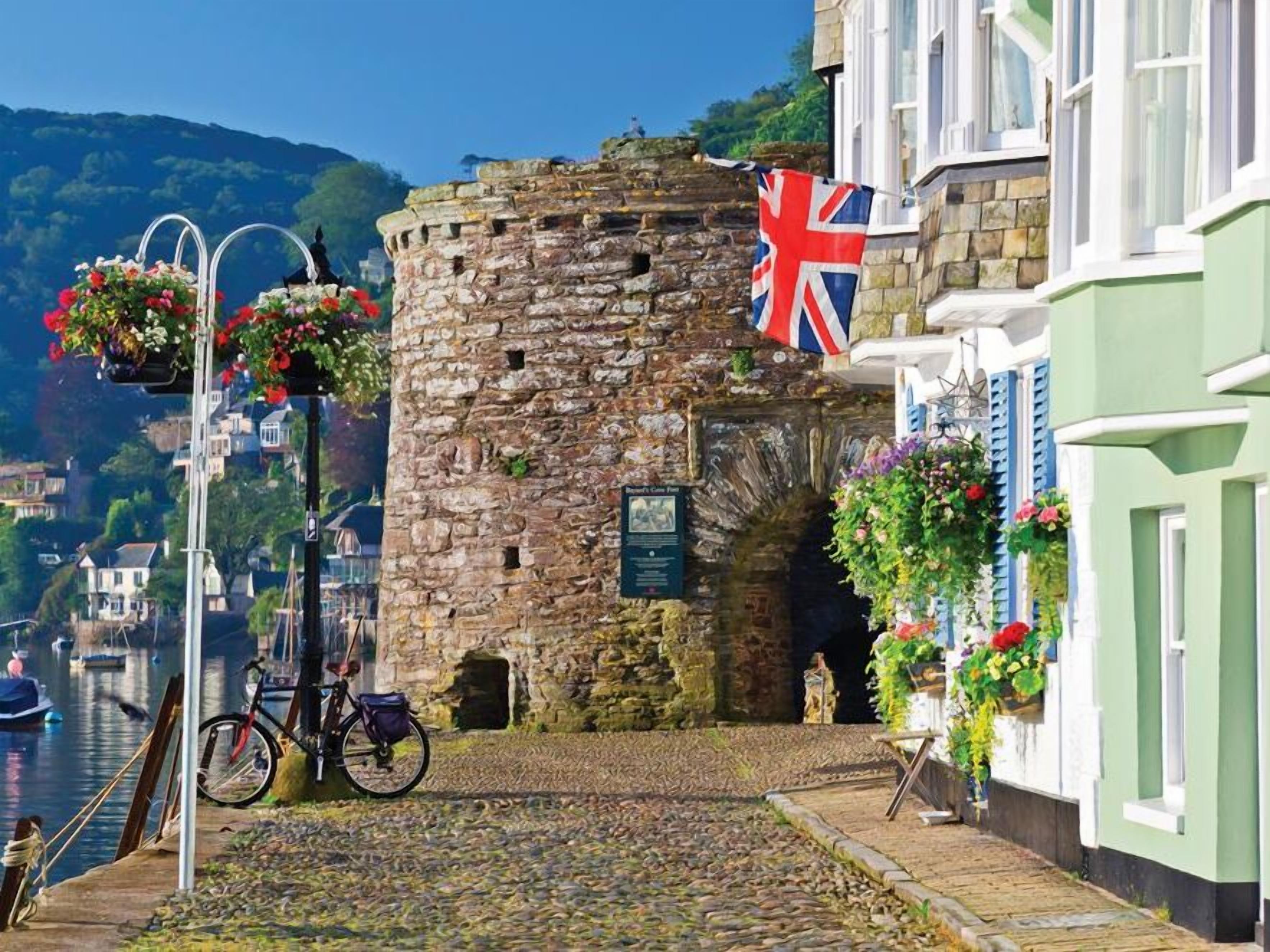 A cobblestone street with a stone tower, a bicycle, and a flag.