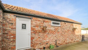 A brick building with a white door, a small window, and a tiled roof.