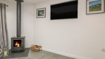 A room with a wood-burning stove, a TV mounted on the wall, and a framed picture above it.