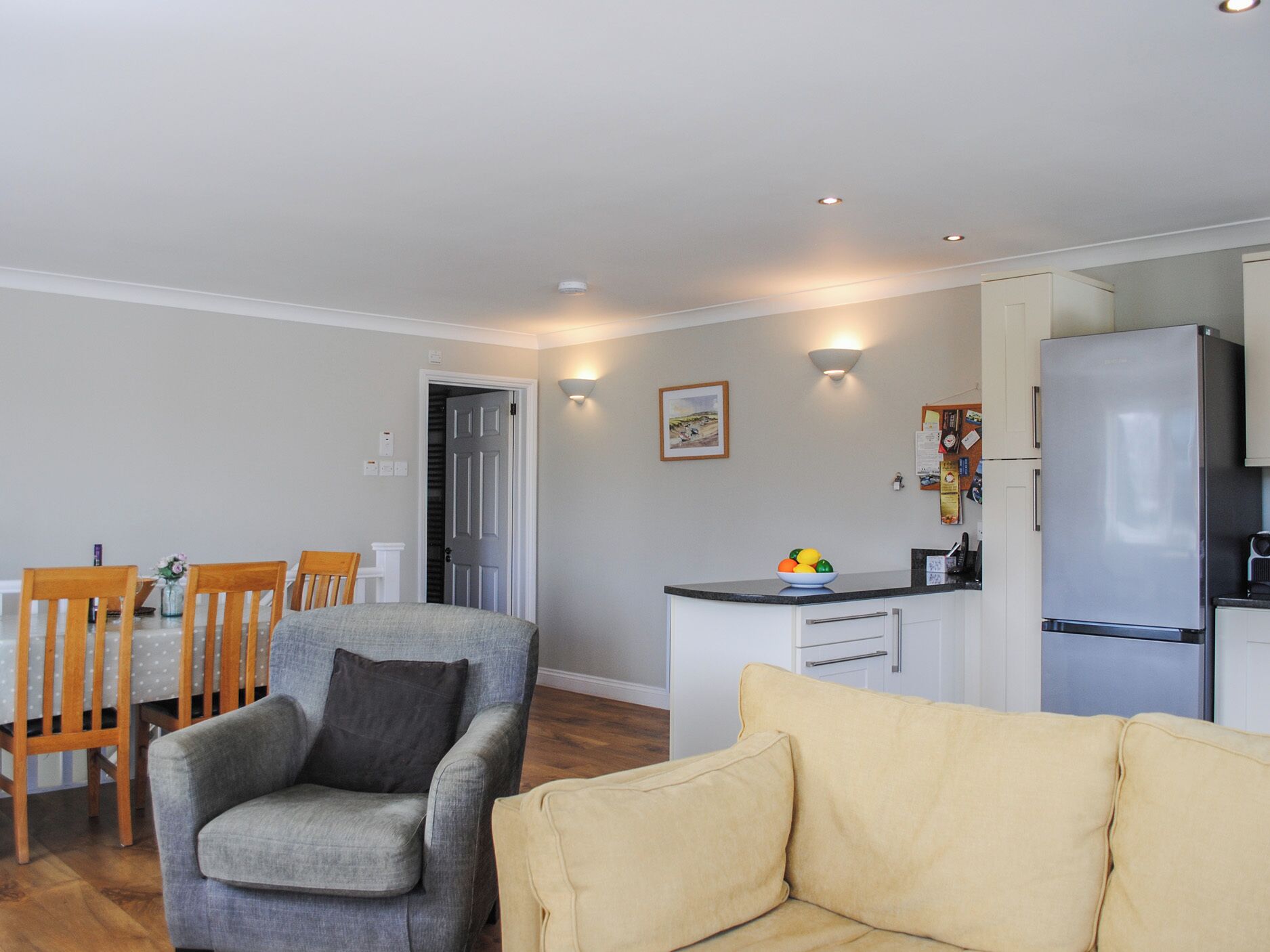 A compact living space with a dining area, a sofa, a kitchenette, and a door leading to a closet.