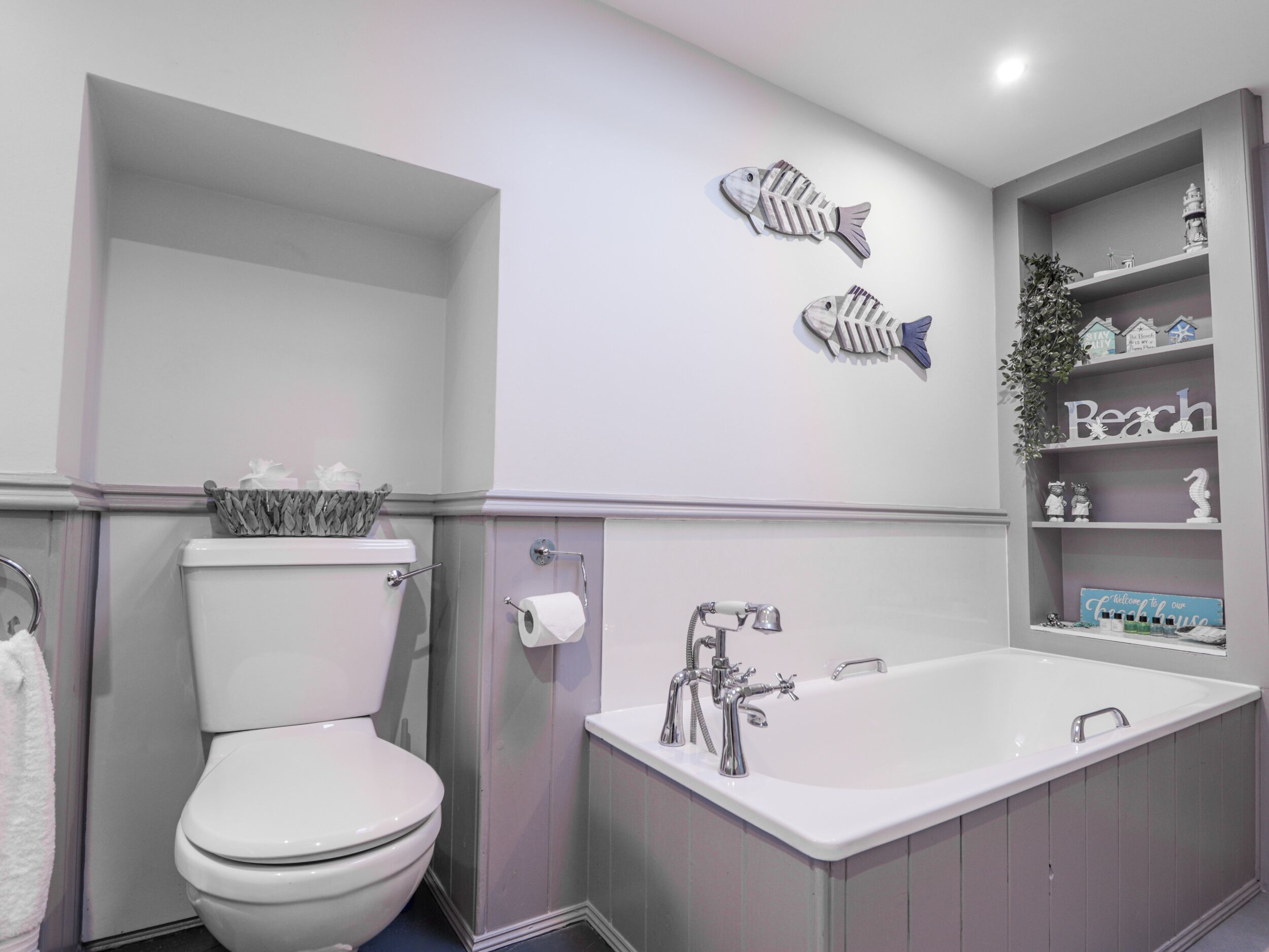 Un baño con inodoro, bañera y repisas decoradas.